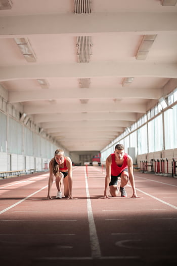 Two athletes in crouch position ready to sprint on an indoor track. HD phone wallpaper