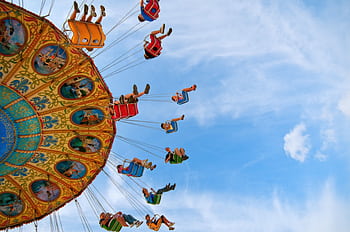 Colorful swing ride at an amusement park with people enjoying a thrilling day under the clear blue sky. HD wallpaper