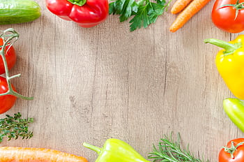 A top view of various fresh organic vegetables arranged on a rustic wooden surface. HD wallpaper