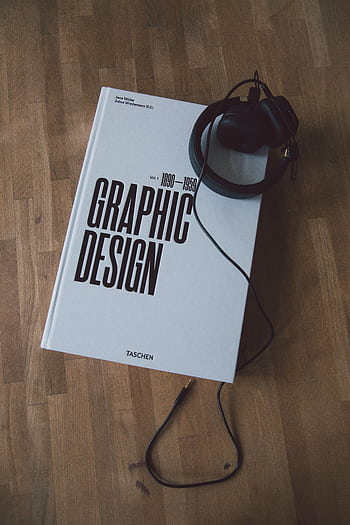Discover graphic design history with this book and heads on a wooden floor. HD phone wallpaper