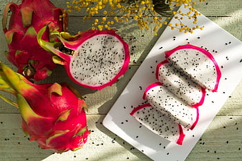 Vibrant dragon fruit slices on wood showcase tropical freshness and healthy eating. HD wallpaper