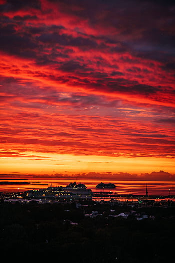 Vivid twilight cityscape with dynamic red and orange afterglow over a bustling harbor. HD phone wallpaper