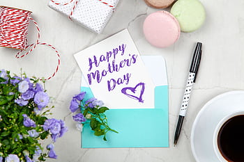 Creative Mother's Day card setup with flowers, coffee, and macarons on a marble table. HD wallpaper