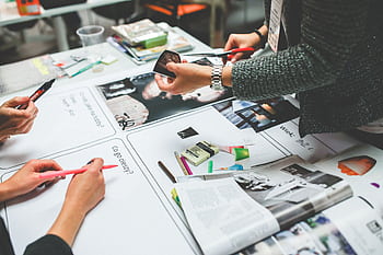 Team members brainstorming and collaborating on a design project in a modern office setting. HD wallpaper