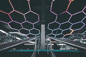 Explore a modern subway station with a futuristic design featuring illuminated geometric patterns and stainless steel railings. HD wallpaper