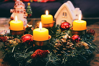 Cozy Christmas display featuring candles, ornaments, and festive wreath in warm candlelight. HD wallpaper