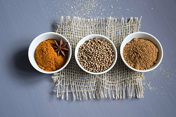 Flat lay of aromatic spices in bowls on a textured mat. HD wallpaper