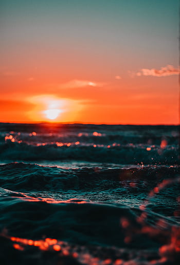 Stunning sunset over ocean waves with vivid colors and sun flare, creating a serene seascape. HD phone wallpaper