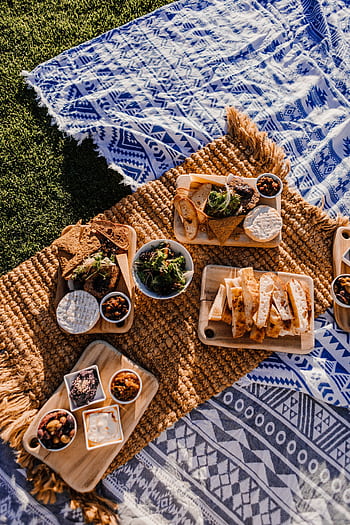 Delicious gourmet picnic spread outdoors with assorted bread, cheeses, and snacks. HD phone wallpaper
