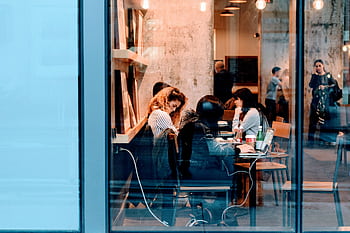 Group of adults working inside a stylish city cafe, showcasing modern work culture. HD wallpaper