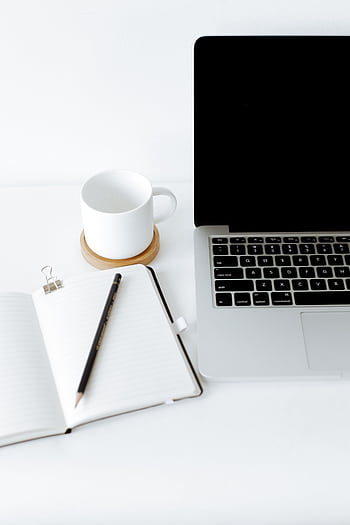 A minimalist workspace featuring a laptop, notebook, and coffee cup in a bright setting. HD phone wallpaper