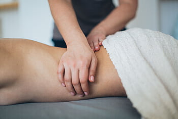 Close-up of a woman receiving a therapeutic massage in a serene spa setting with a white towel. HD wallpaper