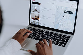 Hands typing on laptop searching Airbnb for accommodation options with map view. HD wallpaper