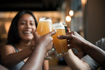 Friends enjoying drinks and toasting in a lively indoor bar setting. HD wallpaper