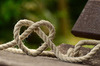 Close-up of twine forming a heart shape on a rustic wooden table outdoors. HD wallpaper