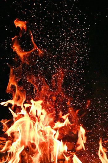 Vivid orange flames and sparks dance against a mysterious black backdrop. HD phone wallpaper