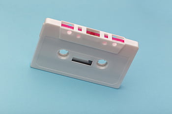 Vintage white cassette tape against a vibrant blue backdrop, capturing classic audio technology nostalgia. HD wallpaper