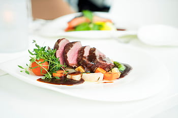 Elegant presentation of sliced beef with herbs and sauce, capturing fine dining ambiance. HD wallpaper