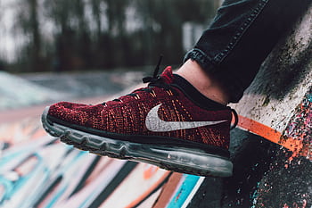 Vibrant red sneaker displayed against a dynamic graffiti wall in outdoor setting. HD wallpaper