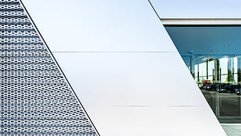 Sleek modern facade showcasing geometric patterns and reflections in urban setting. HD wallpaper