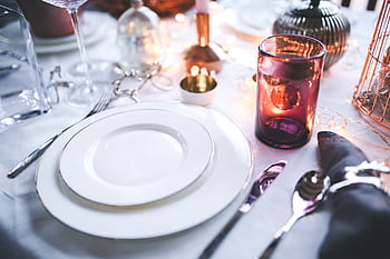 A beautifully arranged dinner table with elegant tableware and warm candle lighting for a festive occasion. HD wallpaper