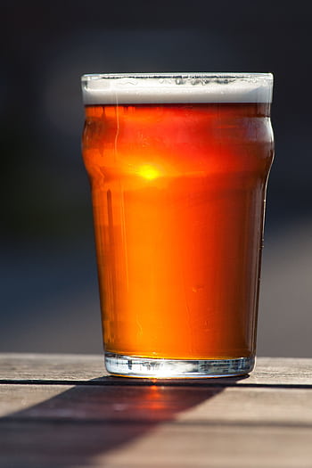 A refreshing pint of amber ale in sunlight on an outdoor table. HD phone wallpaper