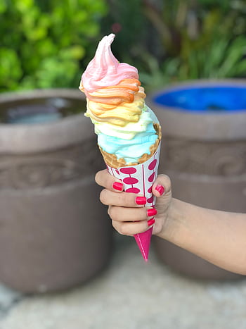 Vibrant rainbow ice cream cone held outdoors, perfect for summer days in Orlando, Florida. HD phone wallpaper