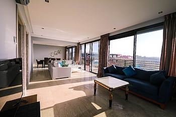 Bright and airy contemporary living room with furniture and large windows overlooking a city view. HD wallpaper