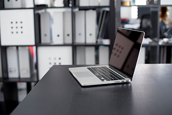 MacBook Pro displayed on a minimalist office desk with shelves in the background. HD wallpaper
