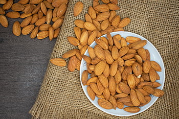 Top view of almonds in a white bowl on a burlap surface, highlighting healthy snacking. HD wallpaper