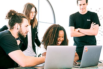 A diverse group of young professionals collaborating enthusiastically in a bright, modern workspace. HD wallpaper