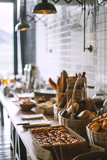 Warm and inviting bakery setup with fresh bread and pastries in a rustic café setting. HD phone wallpaper
