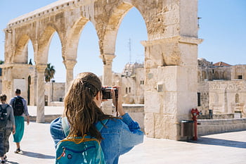 A tourist graphs the ancient stone arches in Jerusalem's Old Town, capturing the essence of travel and history. HD wallpaper