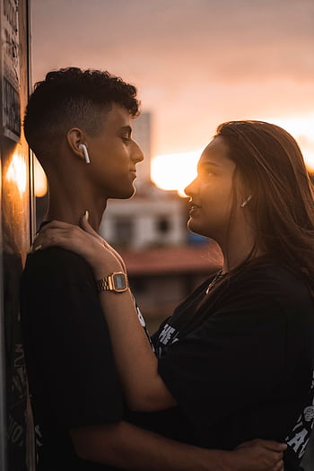 A young couple sharing a tender moment outdoors during sunset, symbolizing love and togetherness. HD phone wallpaper