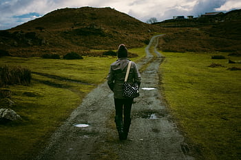 Person walking on a scenic countryside trail, embracing solitude and nature. HD wallpaper