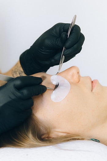 Close-up of a beautician applying eyelash extensions to a client in a salon setting. HD phone wallpaper