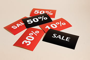 Red and black sale tags showing various discount percentages on a beige background. HD wallpaper