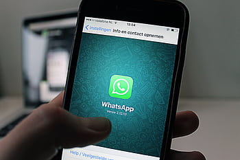 A smart displaying the WhatsApp application screen held by a person. HD wallpaper