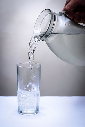 Crystal clear water being poured into a glass from a pitcher. Refreshing and hydrating concept. HD phone wallpaper