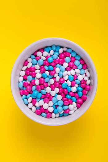 A white bowl filled with colorful candy against a vivid yellow background, perfect for food promotions. HD phone wallpaper