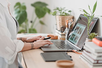 lance designer working from home using a laptop and digital tablet, surrounded by plants. HD wallpaper