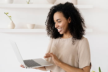 Smiling woman working on a laptop in a modern home office, highlighting lance lifestyle. HD wallpaper