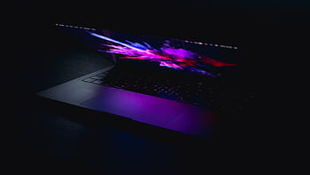 A laptop displaying a vibrant abstract design in low light, highlighting artistic and digital design concepts. HD wallpaper