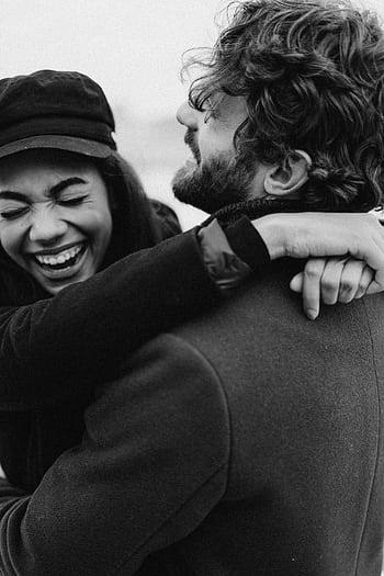 Black and white of a joyful couple embracing and laughing, capturing a loving moment. HD phone wallpaper