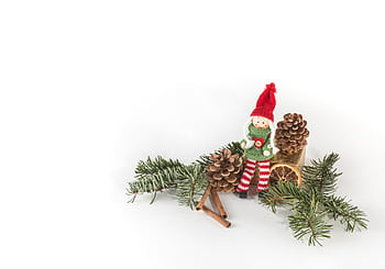 A charming Christmas decoration featuring a knit doll surrounded by pine cones and greenery. HD wallpaper