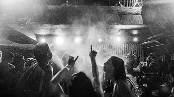 A dynamic black and white captures a vibrant nightclub crowd dancing amidst smoke and lights. HD wallpaper