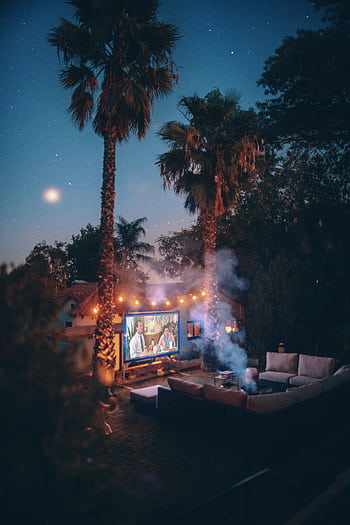 Relaxing outdoor movie night setup with projector under a starry sky in Los Angeles. HD phone wallpaper