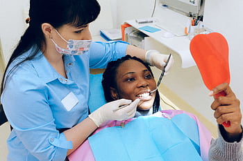 A female dentist checks a patient's teeth during a dental appointment. HD wallpaper