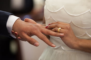 Close-up of a bride and groom exchanging rings during their wedding ceremony, symbolizing love and unity. HD wallpaper