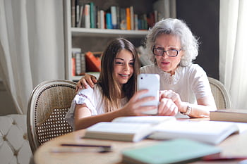 A grandmother and granddaughter bonding over a smart at home, showcasing generational connection. HD wallpaper